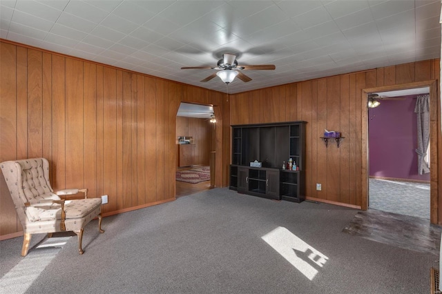 unfurnished room with baseboards, carpet floors, wooden walls, and ceiling fan