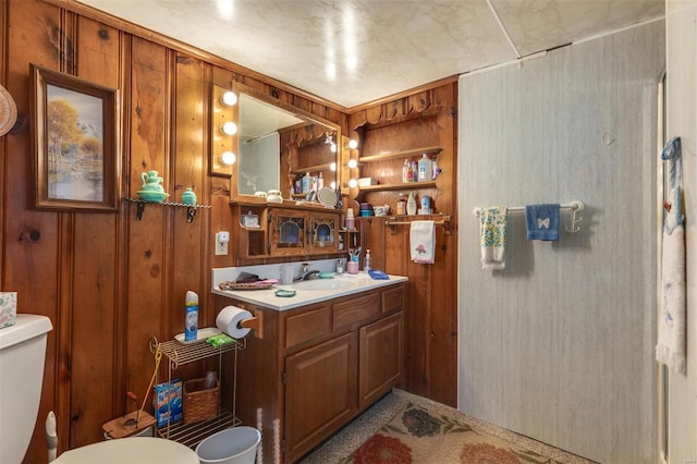 full bath with vanity, toilet, and wood walls