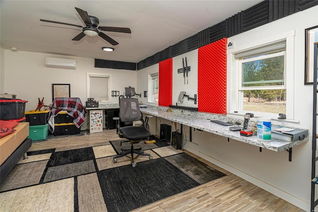 office area featuring a wall unit AC, wood finished floors, and ceiling fan