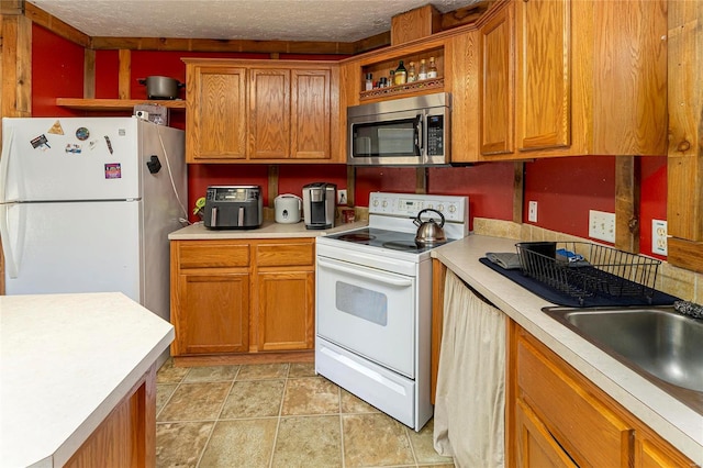 kitchen featuring brown cabinetry, white appliances, light countertops, and open shelves