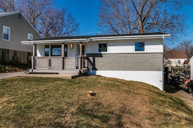 view of front of house featuring a front yard, brick siding, and covered porch