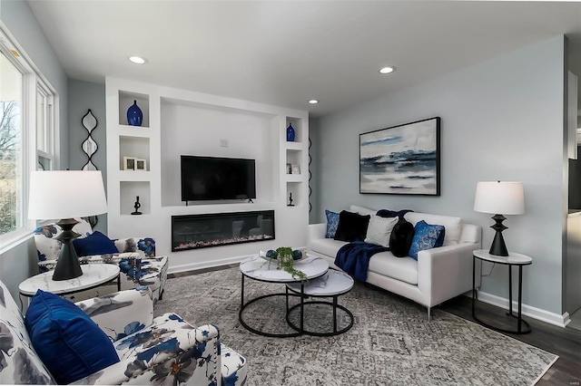 living area with recessed lighting, baseboards, built in shelves, and wood finished floors