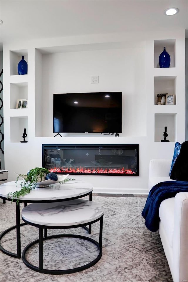 living area featuring a glass covered fireplace and built in features