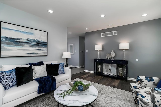 living room with recessed lighting, visible vents, baseboards, and wood finished floors