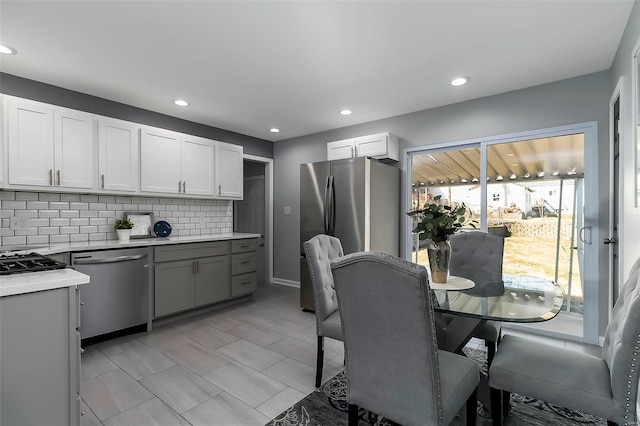 kitchen featuring tasteful backsplash, white cabinets, stainless steel appliances, and light countertops