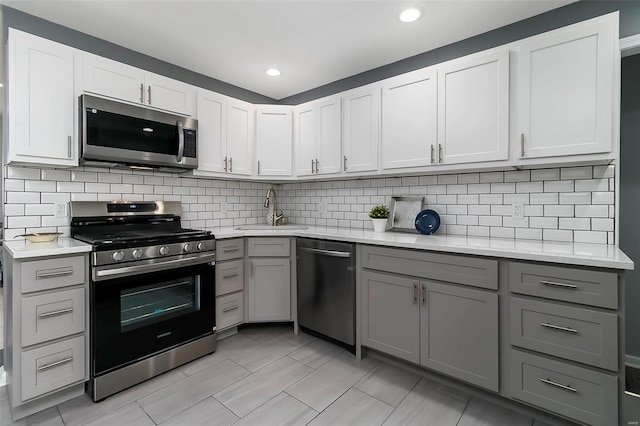 kitchen with light countertops, gray cabinets, appliances with stainless steel finishes, and a sink