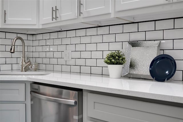 interior details with light stone counters, white cabinetry, a sink, decorative backsplash, and dishwasher