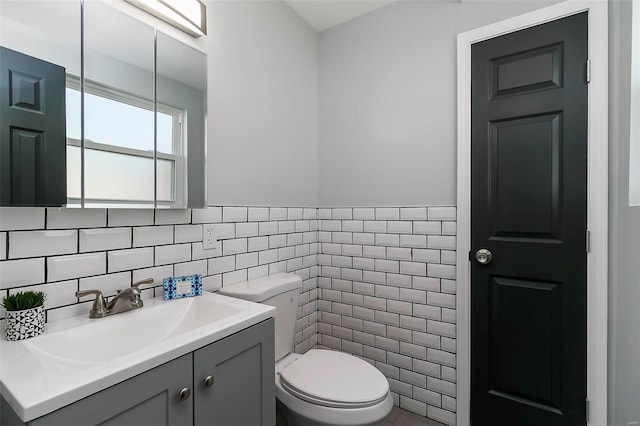 bathroom with toilet, tile walls, and vanity