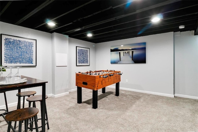 rec room with baseboards and light colored carpet