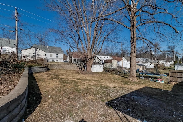 view of yard featuring a trampoline, fence, and a residential view