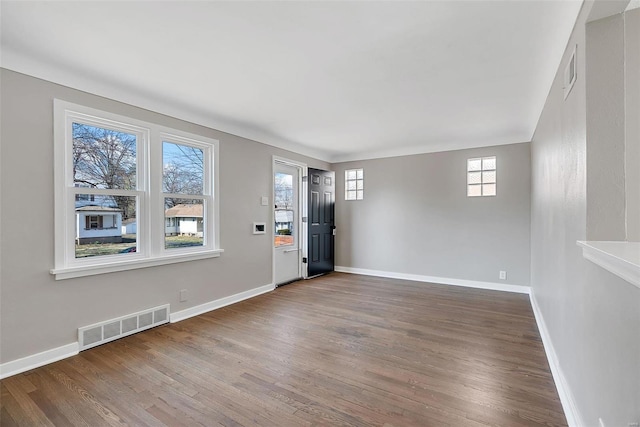 empty room with wood finished floors, visible vents, and baseboards