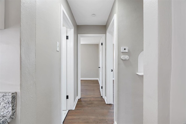 hallway featuring wood finished floors and baseboards