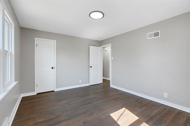 unfurnished bedroom with visible vents, baseboards, and dark wood-style floors