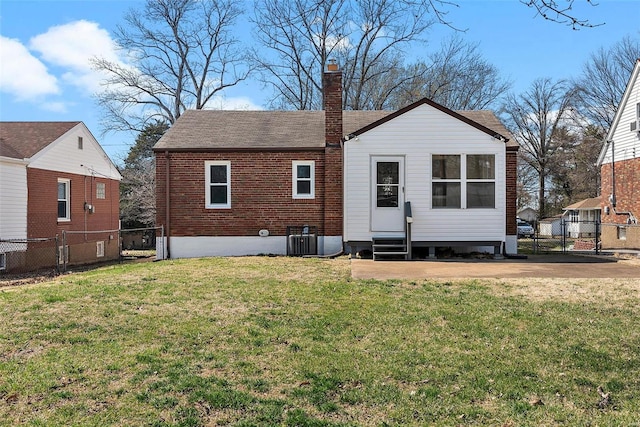 back of house featuring a yard, a fenced backyard, a chimney, and entry steps