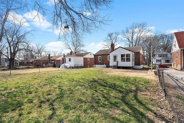 back of property featuring entry steps, a fenced backyard, a residential view, and a lawn