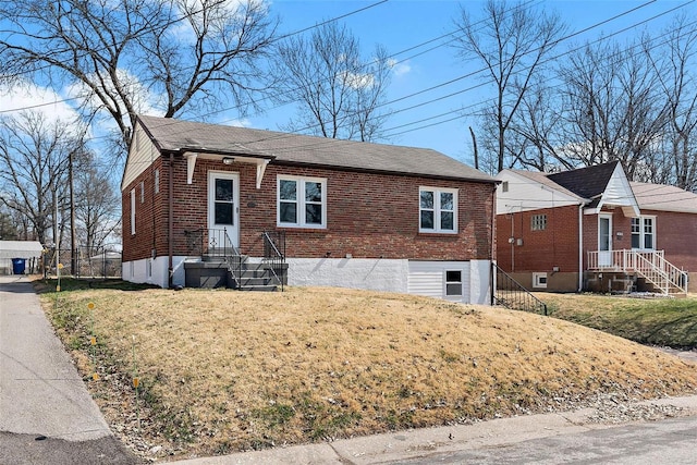 bungalow-style house featuring brick siding and a front yard