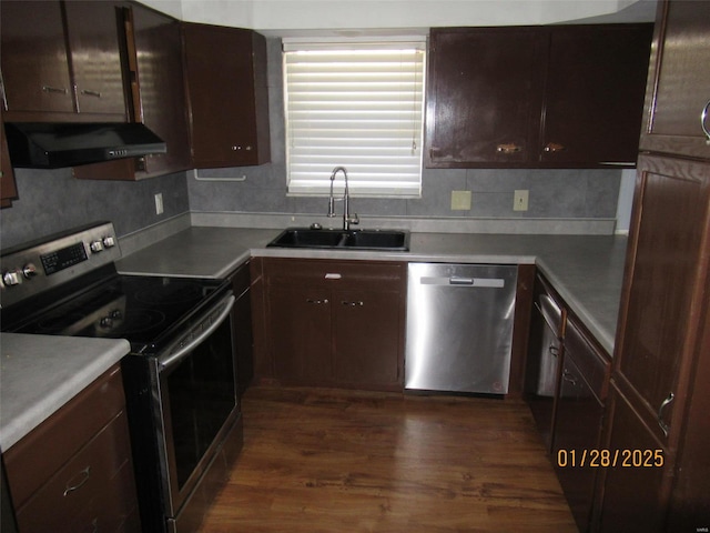 kitchen featuring dark wood-style floors, a sink, under cabinet range hood, appliances with stainless steel finishes, and tasteful backsplash