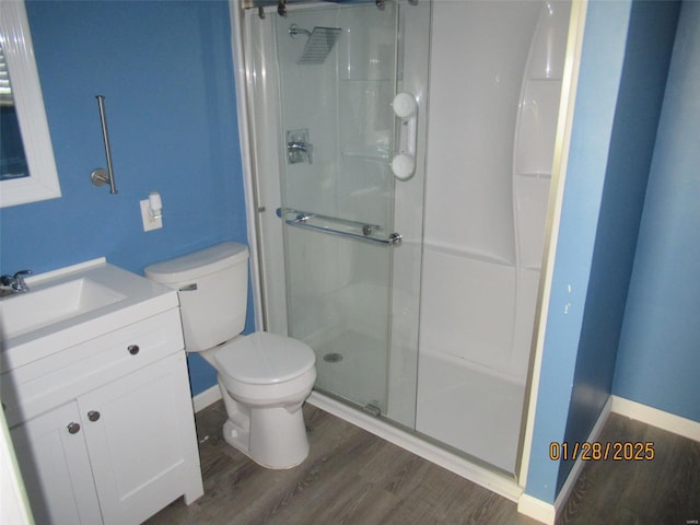 bathroom featuring vanity, toilet, wood finished floors, and a stall shower