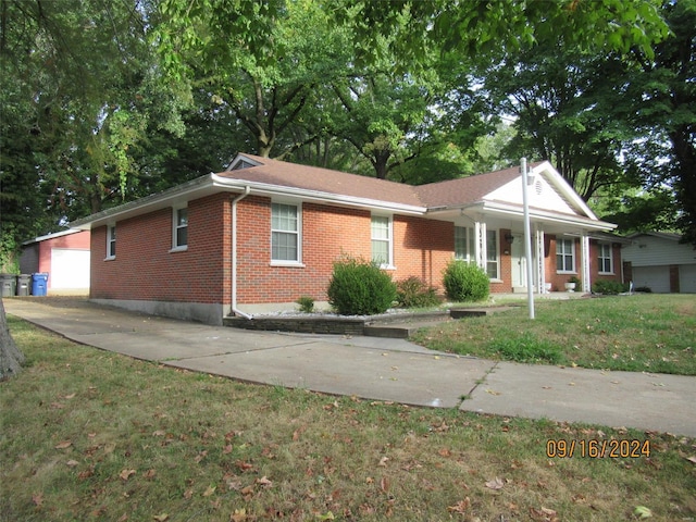 ranch-style house featuring a front yard, an outbuilding, concrete driveway, a garage, and brick siding