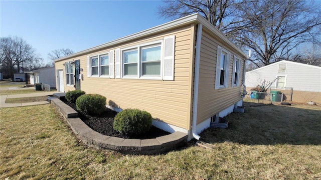 view of property exterior with central AC unit, a lawn, and fence