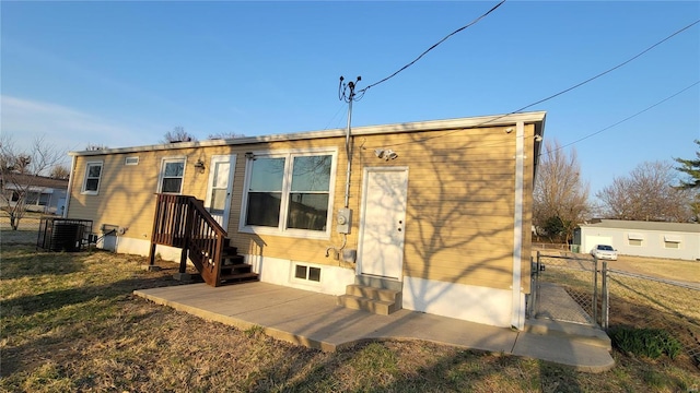 rear view of house with a gate, central AC unit, and fence