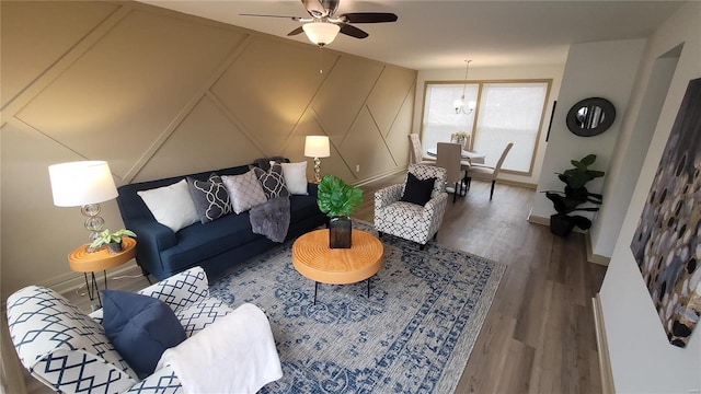 living area with baseboards, wood finished floors, ceiling fan, and a decorative wall