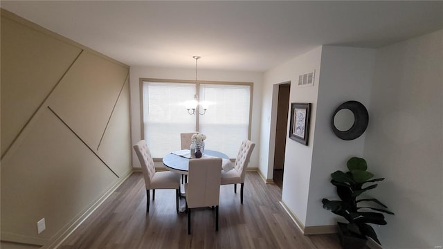 dining area with visible vents, baseboards, an inviting chandelier, and wood finished floors