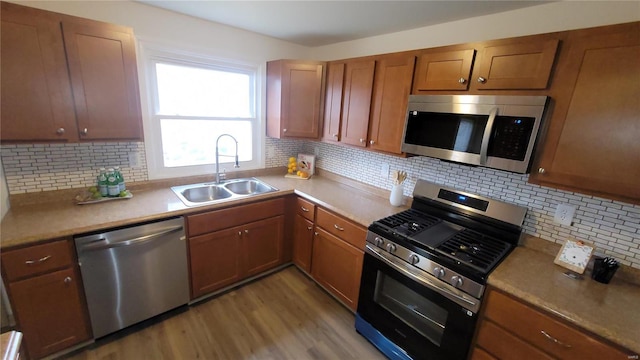 kitchen featuring a sink, tasteful backsplash, light wood finished floors, and stainless steel appliances