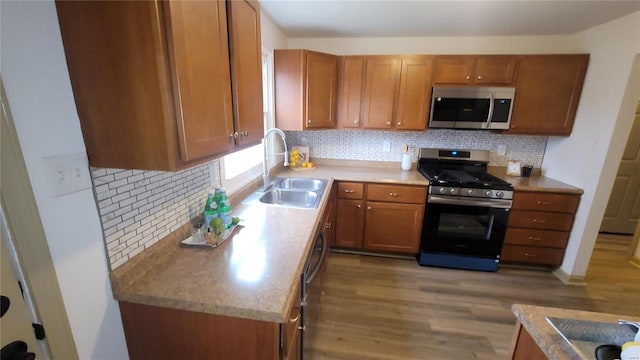 kitchen featuring light wood-type flooring, brown cabinets, a sink, backsplash, and stainless steel appliances