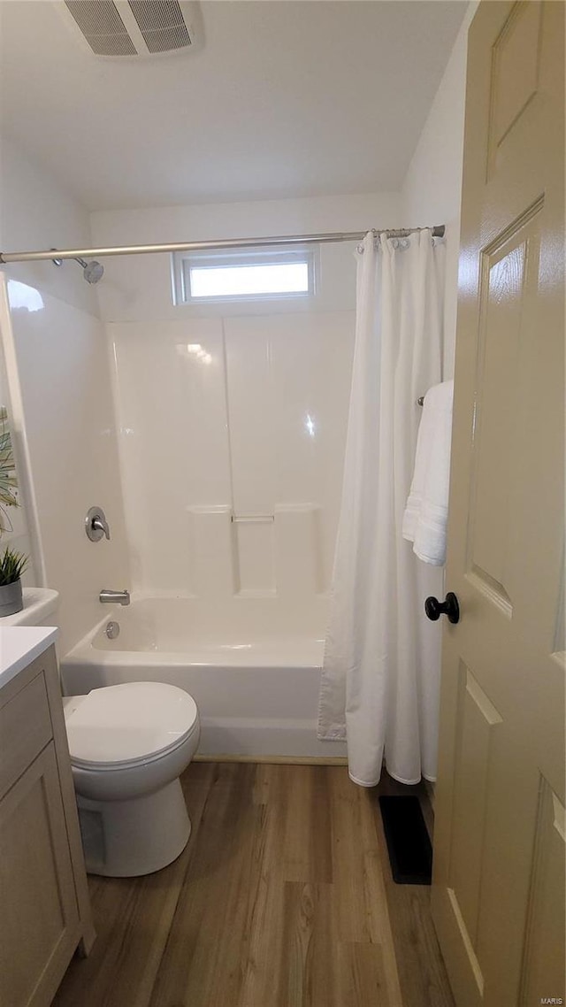 bathroom featuring visible vents, toilet, shower / bath combo, wood finished floors, and vanity