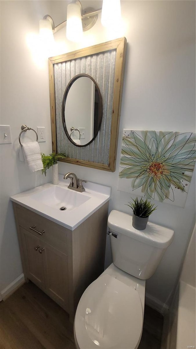 bathroom with toilet, vanity, and wood finished floors