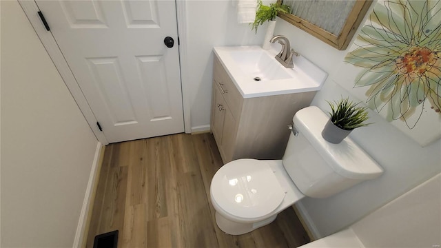 bathroom with toilet, vanity, and wood finished floors