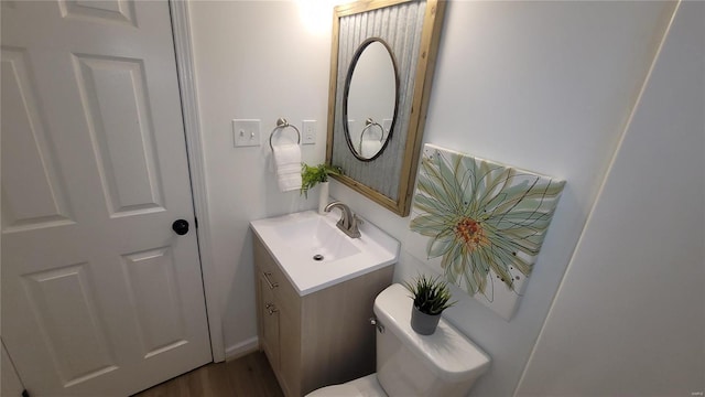 half bath featuring toilet, vanity, and wood finished floors