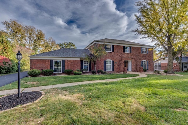 colonial home with brick siding and a front yard