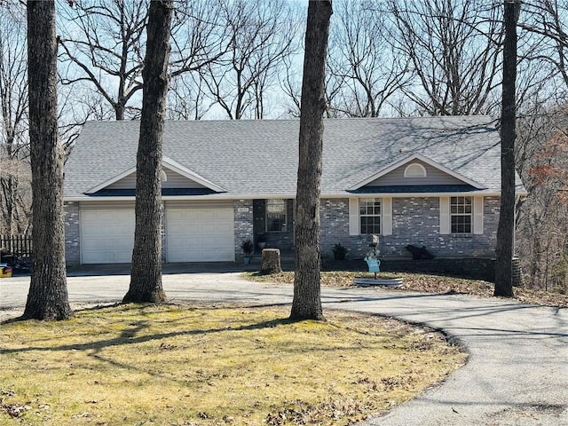 view of front of house featuring brick siding, a front lawn, concrete driveway, roof with shingles, and an attached garage