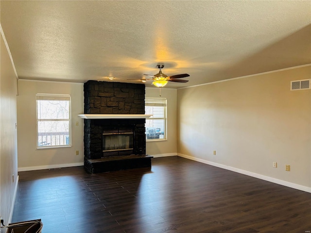 unfurnished living room featuring a ceiling fan, visible vents, a fireplace, dark wood-type flooring, and crown molding