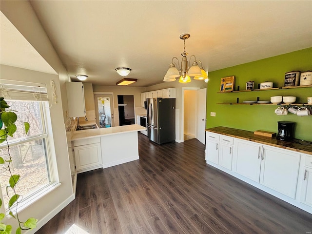 kitchen with white cabinetry, freestanding refrigerator, an inviting chandelier, and dark wood-style flooring