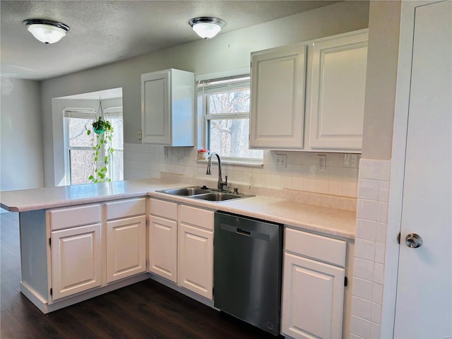 kitchen with a sink, plenty of natural light, dishwasher, and a peninsula