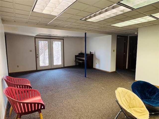 living area with carpet, a paneled ceiling, and baseboards