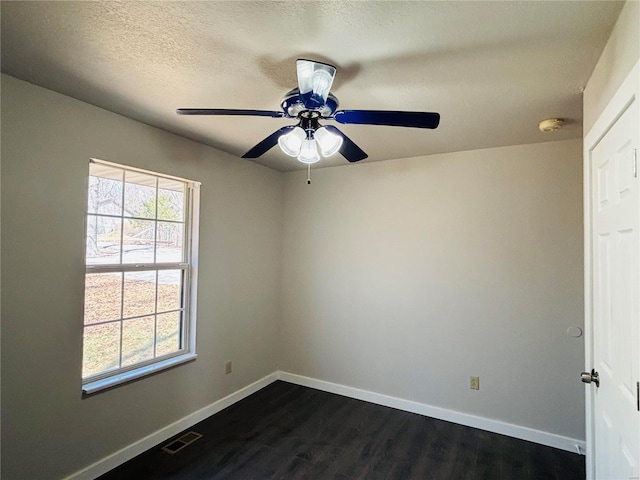 spare room featuring visible vents, ceiling fan, baseboards, a textured ceiling, and dark wood-style flooring