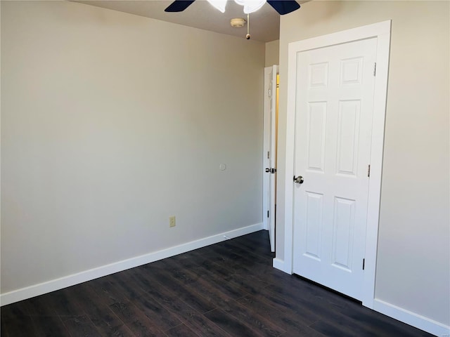 empty room with dark wood finished floors, baseboards, and a ceiling fan