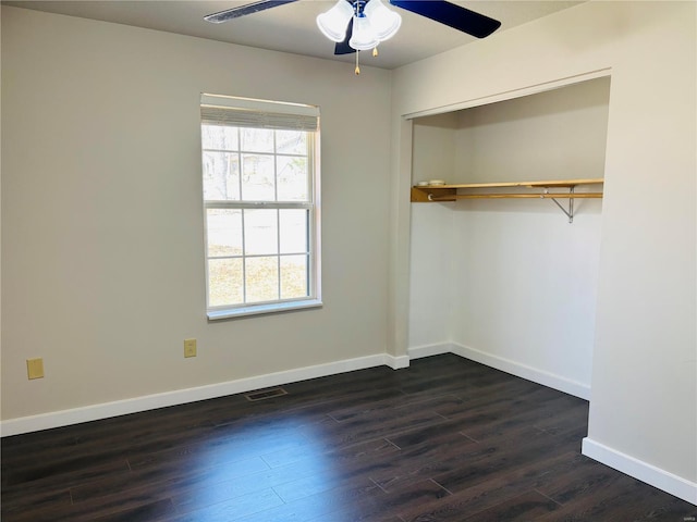 unfurnished bedroom featuring a ceiling fan, baseboards, visible vents, dark wood-type flooring, and a closet