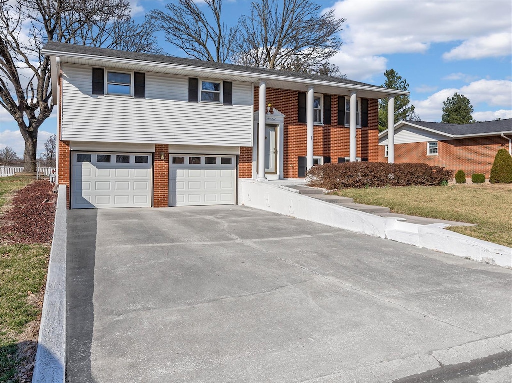 bi-level home with a garage, brick siding, and driveway