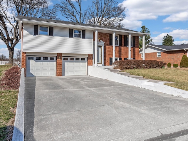 bi-level home with a garage, brick siding, and driveway