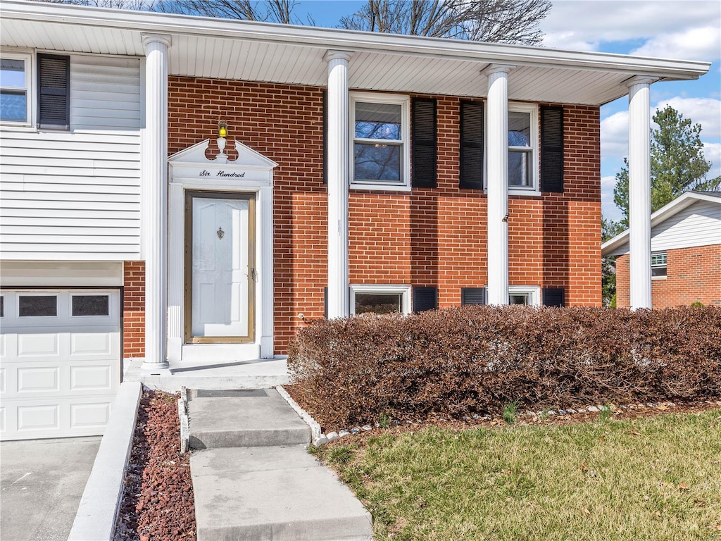 entrance to property featuring a garage and brick siding