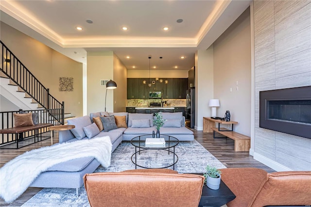 living area featuring baseboards, stairs, recessed lighting, a tile fireplace, and dark wood-style flooring