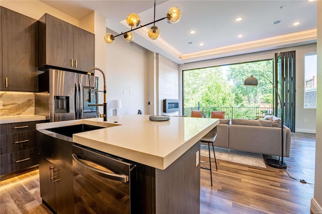 kitchen with dishwasher, wood finished floors, stainless steel fridge with ice dispenser, and a center island with sink