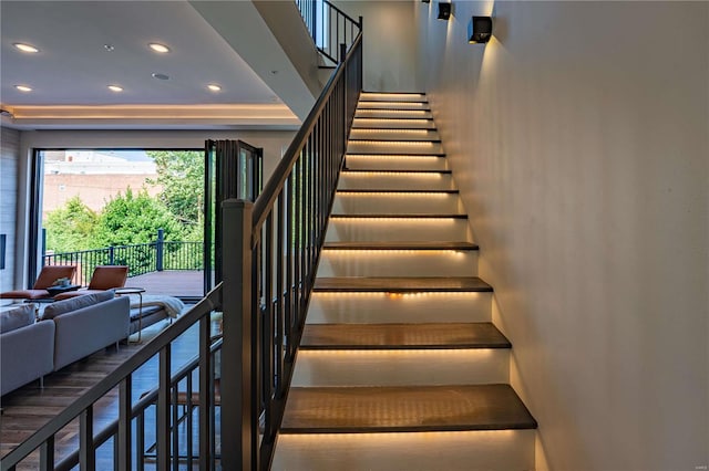 stairway with recessed lighting and a tray ceiling