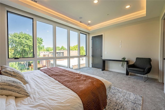 carpeted bedroom with recessed lighting, multiple windows, baseboards, and a tray ceiling