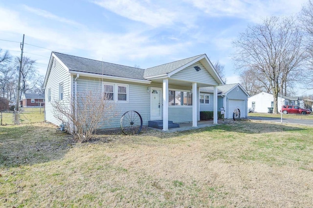 view of front facade featuring a detached garage, roof with shingles, a front yard, and fence